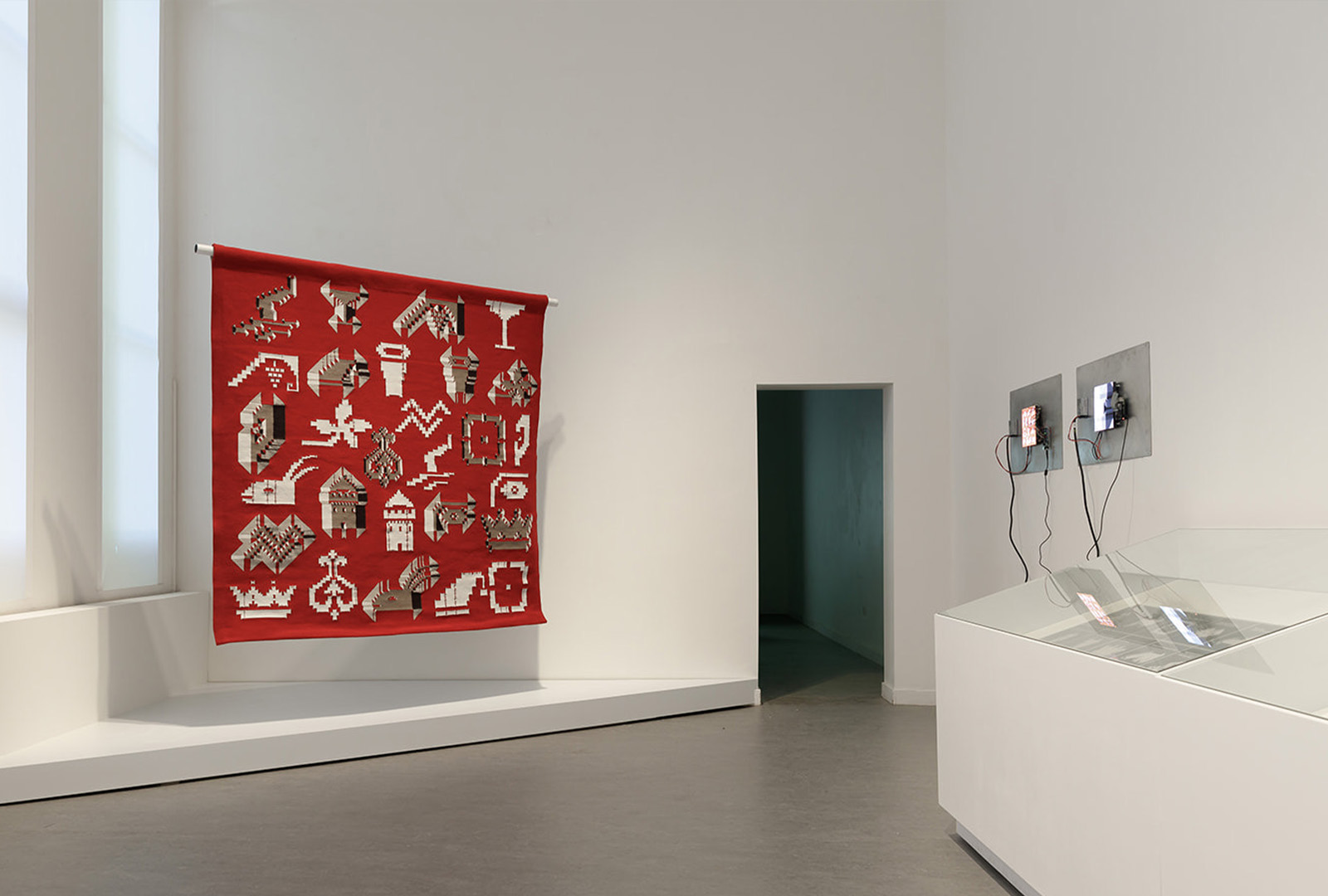 Installation view showing tapestry and LED screens together.